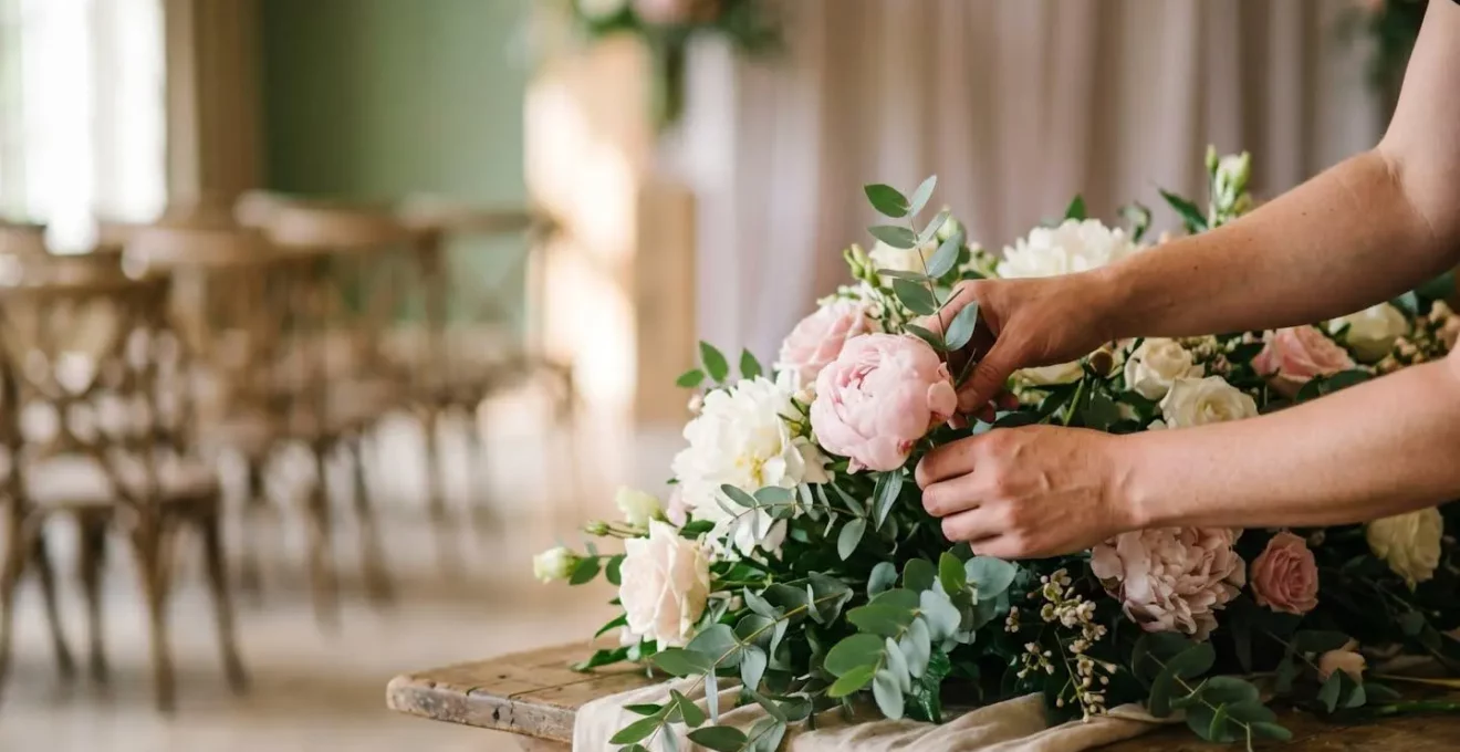 Fleuriste finalisant une composition florale fraîche peu avant la cérémonie