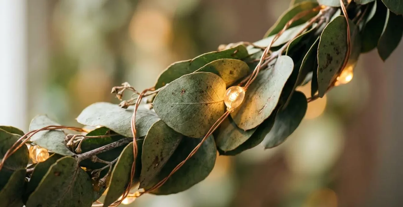 Gros plan sur l'entrelaçement de guirlandes LED et de feuillage naturel montrant la texture et les détails